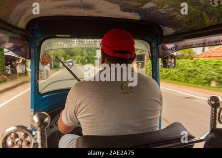 BENTOTA, SRI LANKA - NOV 16, 2019 : le sunny view depuis l'intérieur du taxi Tuk Tuk, derrière le pilote comme il est entraîné le long d'une route de campagne avec les passen Banque D'Images