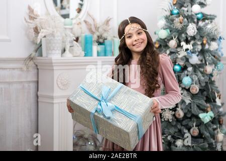 Les traditions familiales. Cadeau de Noël. Petite fille de cadeaux reçus. Meilleurs cadeaux de Noël. Enfant heureux de son cadeau. Petit fille en robe élégante et boîte-cadeau de Noël arrière-plan. Banque D'Images