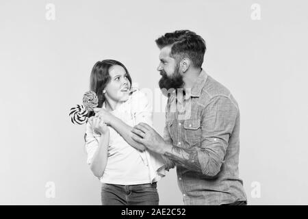 C'est la mienne. mon dessert seulement. candy shop. enfance heureuse. Fille et père de manger des bonbons. hipster barbu homme est bon père. petite fille et papa tenir sucette colorés. été vibes. famille heureuse. Banque D'Images