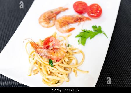 Linguine aux crevettes et tomates cerises. Les crevettes de la Méditerranée sont des crustacés, la sauce est aussi accompagné par le poivre et fres Banque D'Images