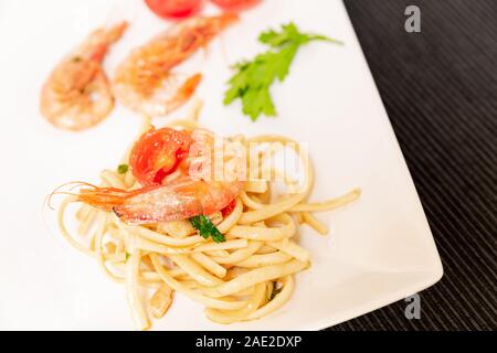 Linguine aux crevettes et tomates cerises. Les crevettes de la Méditerranée sont des crustacés, la sauce est aussi accompagné par le poivre et fres Banque D'Images