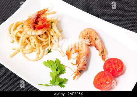 Linguine aux crevettes et tomates cerises. Les crevettes de la Méditerranée sont des crustacés, la sauce est aussi accompagné par le poivre et fres Banque D'Images