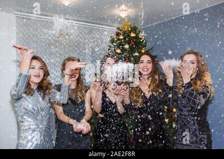 Happy cheerful pretty women jeter des confettis, neige et sourire à la partie. Nouvelle année, des vacances, de la célébration, les gens concept Banque D'Images