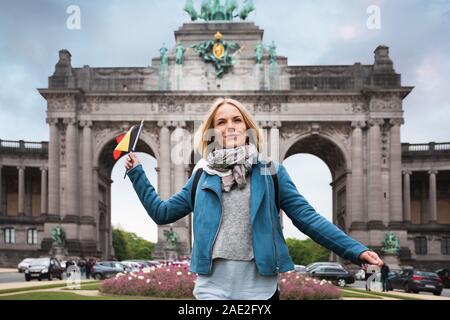 Jeune femme dans des vêtements décontractés avec la Belgique drapeau dans les mains sur fond de l'Arc de Triomphe en Cinquantennaire Park à Bruxelles, Belgique Banque D'Images