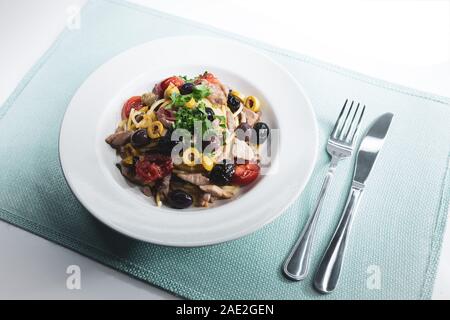 Spaghetti avec sauce composée de : thon, câpres, olives, piment sicilien, tomates cerises et une poignée de persil Banque D'Images