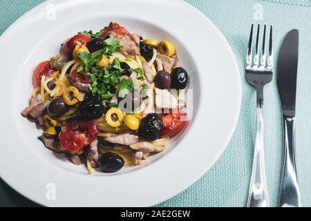 Spaghetti avec sauce composée de : thon, câpres, olives, piment sicilien, tomates cerises et une poignée de persil Banque D'Images