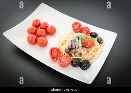 Spaghetti avec sauce composée de : thon, câpres, olives, piment sicilien, tomates cerises et une poignée de persil Banque D'Images