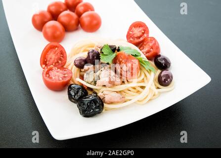 Spaghetti avec sauce composée de : thon, câpres, olives, piment sicilien, tomates cerises et une poignée de persil Banque D'Images