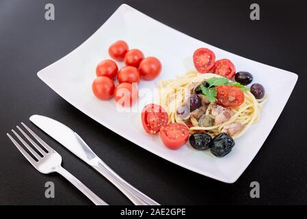 Spaghetti avec sauce composée de : thon, câpres, olives, piment sicilien, tomates cerises et une poignée de persil Banque D'Images