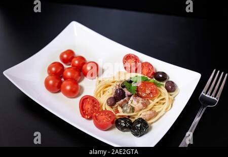 Spaghetti avec sauce composée de : thon, câpres, olives, piment sicilien, tomates cerises et une poignée de persil Banque D'Images