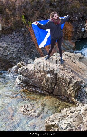 Young woman holding rocks drapeau écossais au conte de piscines, river cassante, Isle of Skye, Scotland, UK en Mars Banque D'Images