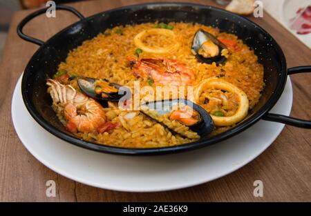 La Paella isolé sur fond foncé naturel, cuisine traditionnelle espagnole, paella aux fruits de mer dans la poêle avec les moules, les langoustines, la langoustine et de calmars. Banque D'Images