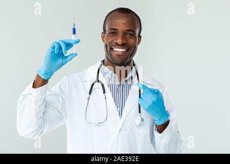 L'expérience joyeuse doctor holding a syringe against white background Banque D'Images