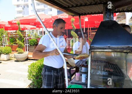 Shkodër, Albanie, le 4 juillet 2019 : Un vendeur prépare un hot-dog avec cevapcici Banque D'Images