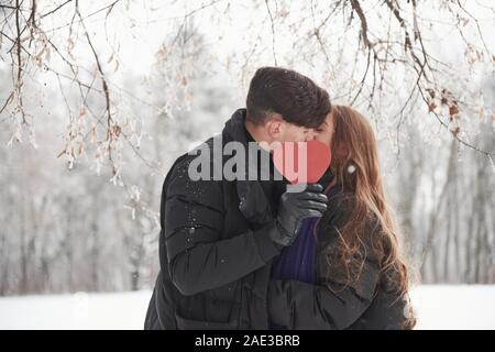 Kiss par cencored cœur rouge. Merveilleuse jeune couple a bon temps ensemble dans la forêt enneigée Banque D'Images