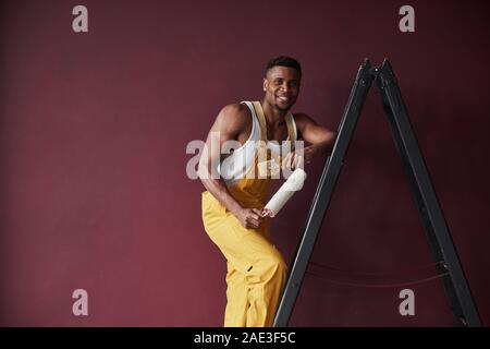 Homme heureux. Young african american travailleur dans l'uniforme jaune ont un emploi Banque D'Images