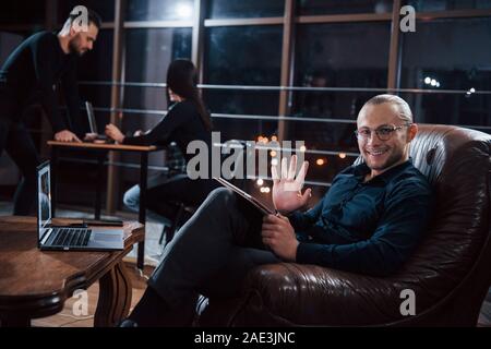 Montrant bonjour geste. De jeunes gens d'affaires de l'équipe travaille sur son projet de nuit au bureau Banque D'Images