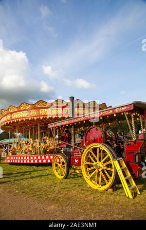 Vintage carousal à vapeur avec dadas étant entraînée par un moteur de traction à vapeur d'époque au Malpas Cheshire rallye d'antan Banque D'Images