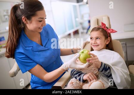 Femme dentiste pomme verte donnant à young patient Banque D'Images