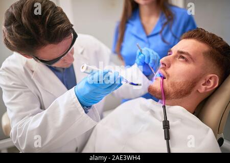 Dentiste au travail avec un patient dans une clinique dentaire Banque D'Images