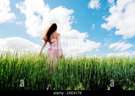 Femme aux cheveux longs dans une robe sur un champ de blé bleu Banque D'Images