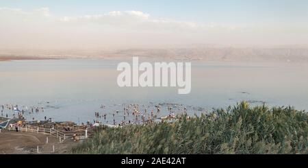 Les touristes profiter de la baignade dans la mer morte au Bikini Beach en Israël au coucher du soleil avec les montagnes de Jordanie moav en arrière-plan et re indigènes communes Banque D'Images