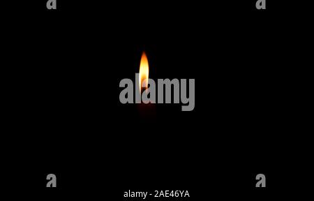 Une lumière candle burning brillamment dans le fond noir Banque D'Images