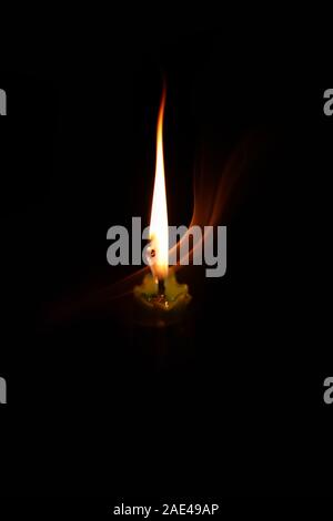Light candle burning brillamment dans le fond noir Banque D'Images