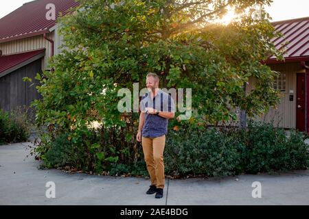 Un homme joyeux rires avec ses yeux fermés au coucher du soleil en face de la maison Banque D'Images