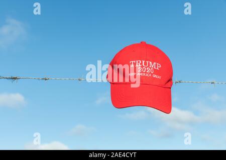 Donald Trump supporters' KAG rouge,Keep America Grande campagne hat / cap sur les barbelés. Métaphore Trump la politique d'immigration des États-Unis, Trump border mur. Banque D'Images