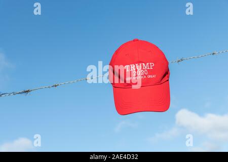 Donald Trump supporters' KAG rouge,Keep America Grande campagne hat / cap sur les barbelés. Métaphore Trump la politique d'immigration des États-Unis, Trump border mur. Banque D'Images