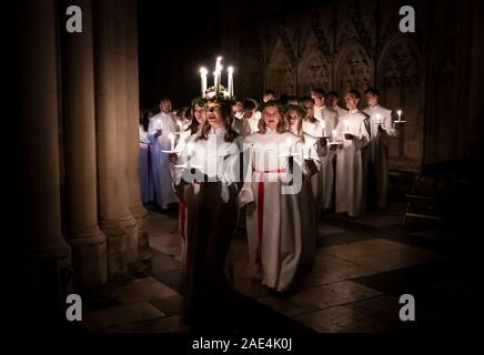 Matilda Bergstrom portant une couronne de bougies symbolisant St Lucy, conduit une procession aux chandelles du choeur nordique au cours de la London Sankta Lucia service à York Minster. Photo date : vendredi 6 décembre 2019. Le service suédois de l'atmosphère est une célébration de Sainte Lucie, une fille sicilien martyrisé pour sa foi chrétienne au quatrième siècle. La couronne symbolise un halo, une écharpe rouge son martyre, et le service célèbre l'occasion de l'entrée de la lumière au cours de l'obscurité de l'hiver. Crédit photo doit se lire : Danny Lawson/PA Wire Banque D'Images