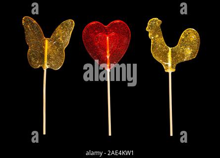 Sucettes au caramel sucre sucré isolé sur fond noir coeur rouge en forme de papillon Coquelet close-up Banque D'Images