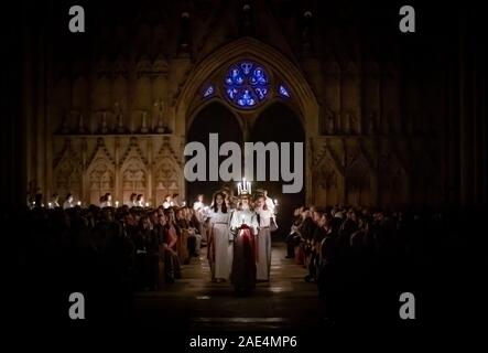 Matilda Bergstrom portant une couronne de bougies symbolisant St Lucy, conduit une procession aux chandelles du choeur nordique au cours de la London Sankta Lucia service à York Minster. Photo date : vendredi 6 décembre 2019. Le service suédois de l'atmosphère est une célébration de Sainte Lucie, une fille sicilien martyrisé pour sa foi chrétienne au quatrième siècle. La couronne symbolise un halo, une écharpe rouge son martyre, et le service célèbre l'occasion de l'entrée de la lumière au cours de l'obscurité de l'hiver. Crédit photo doit se lire : Danny Lawson/PA Wire Banque D'Images