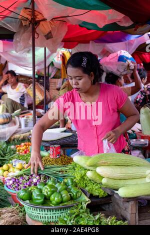 Une femme birmane dans un chemisier rose vente de fruits et légumes frais dans le marché ferroviaire de Mandalay, Myanmar (Birmanie) Banque D'Images