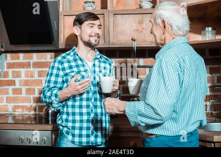 Nice joyeux père et fils prenant le thé ensemble Banque D'Images