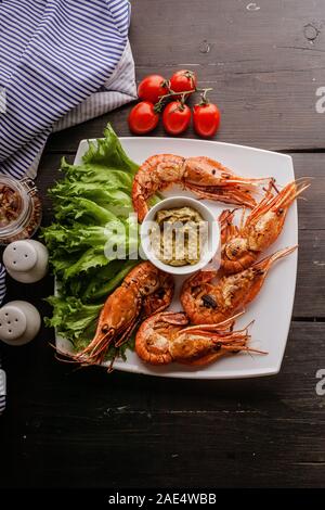 Shot verticale gambas grillées à l'ail et aux citrons sur une plaque blanche avec laitue Banque D'Images
