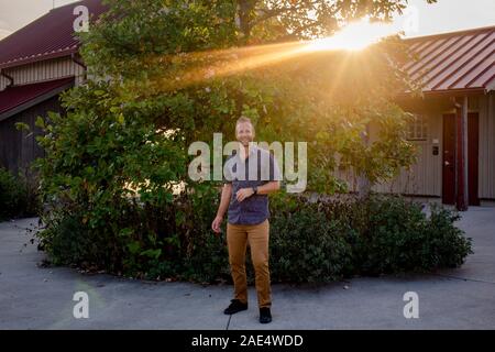 Un couple se tient debout devant son domicile en lightbeams au coucher du soleil d'or Banque D'Images