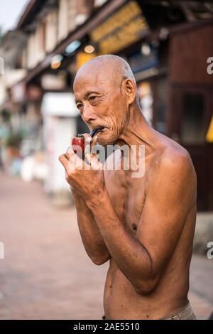 Un vieil homme fume dans la rue du Luang Prabang, Laos, Asie Banque D'Images