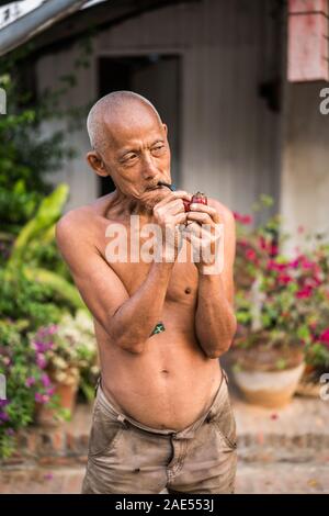 Un vieil homme fume dans la rue du Luang Prabang, Laos, Asie Banque D'Images