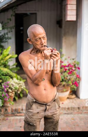 Un vieil homme fume dans la rue du Luang Prabang, Laos, Asie Banque D'Images