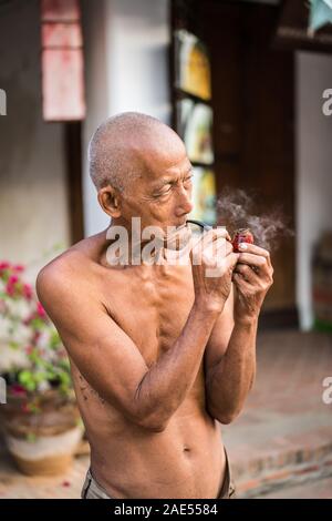 Un vieil homme fume dans la rue du Luang Prabang, Laos, Asie Banque D'Images