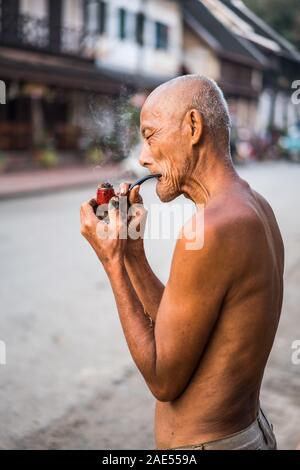 Un vieil homme fume dans la rue du Luang Prabang, Laos, Asie Banque D'Images