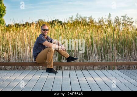 Portrait of a smiling man de l'emplacement sur une promenade dans un parc de zones humides Banque D'Images