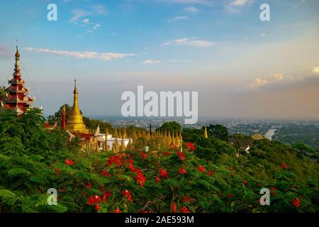 Vue sur la ville de Mandalay au coucher du soleil à partir de Mandalay Hill, avec des fleurs rouges et des pagodes d'or, au Myanmar, anciennement appelé Birmanie Banque D'Images