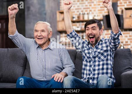 Les hommes gais regarder le football à la maison Banque D'Images