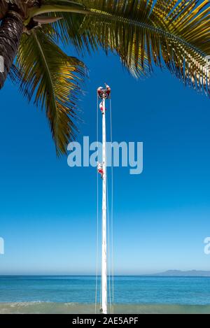 Le Pampantla performersclimb hommes-oiseaux en vol à la rue mexicain haut d'un grand poteau avant d'effectuer sur le Malecon Puerto Vallarta. Banque D'Images