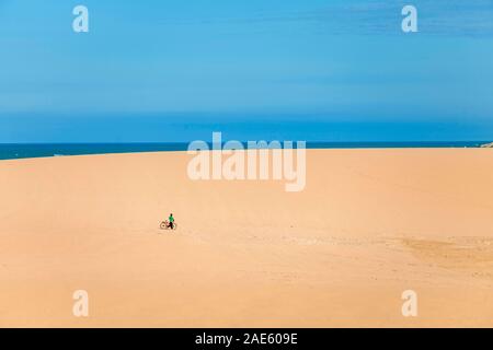 L'homme avec son vélo dans les dunes côtières de Taroa dans la péninsule Guajira du nord de la Colombie. Banque D'Images