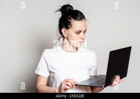 Jeune femme regarde son portable et lit attentivement le mail, il est agréablement surpris par la bonne nouvelle. Banque D'Images