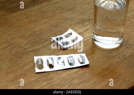 Photo de sachets médecine vide sur une table et le verre d'eau Banque D'Images